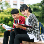 Male and female students sitting and reading books on the stairs