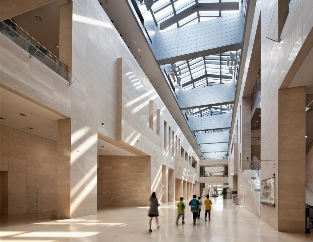 Aula interior National Museum of Korea dengan desain arsitektur modern, pencahayaan alami, dan pengunjung yang berjalan